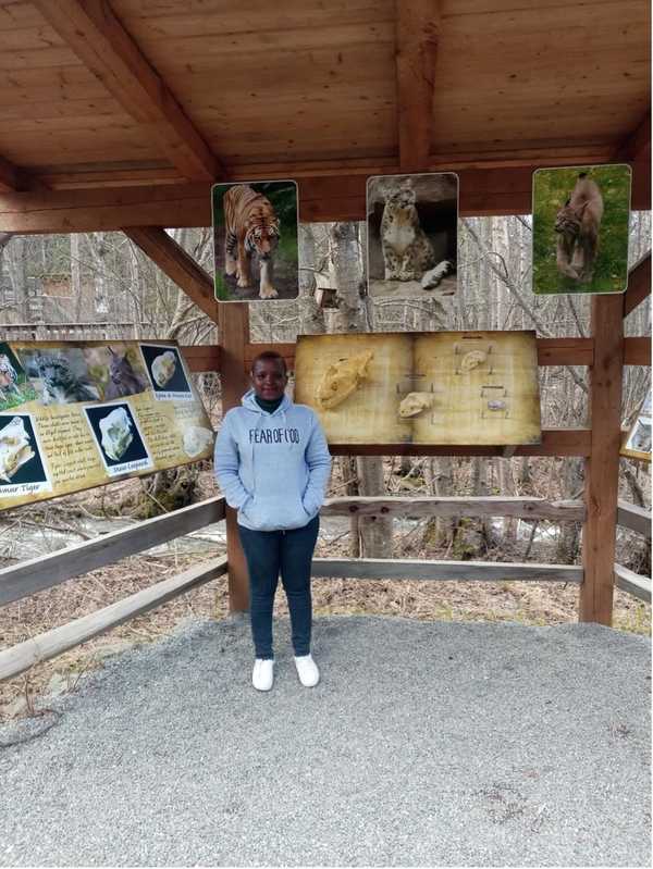 An African woman stands by displays at a zoo