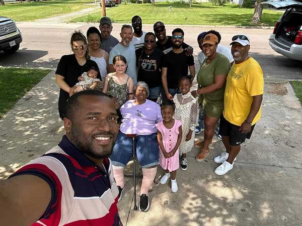 An African man is taking a selfie with a large group of people in the background